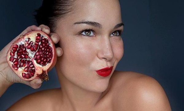Woman holding halved pomegranate